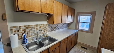 Kitchen with backsplash, light countertops, brown cabinets, and light tile patterned flooring