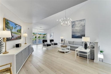 Living area featuring light wood finished floors, a chandelier, and high vaulted ceiling
