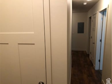 Corridor with electric panel and dark wood-style floors