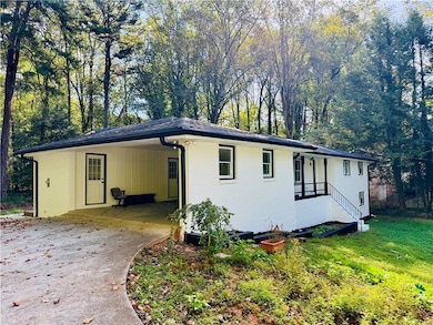 Ranch-style home with a carport, concrete driveway, brick siding, board and batten siding, and a front yard