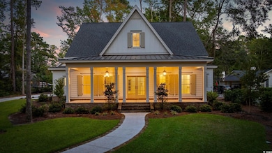 Modern farmhouse style home featuring covered porch, a standing seam roof, a yard, a shingled roof, and a metal roof
