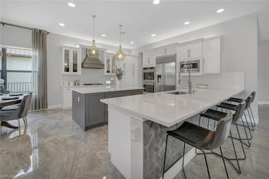 Kitchen with built in appliances, decorative light fixtures, custom range hood, and white cabinets