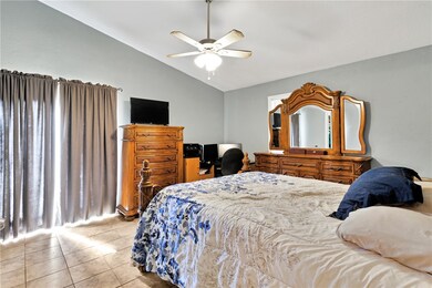 Bedroom featuring vaulted ceiling, light tile patterned flooring, and a ceiling fan