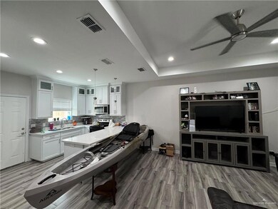 Kitchen with range, stainless steel microwave, light wood-style floors, a sink, and ceiling fan
