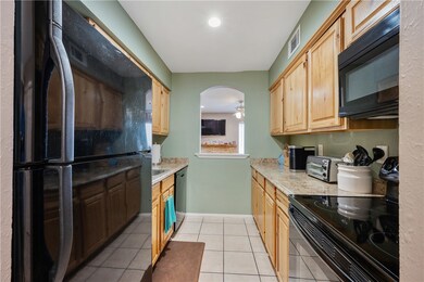 Kitchen with black appliances, light tile patterne