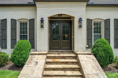 Entrance to property featuring french doors, brick siding, and roof with shingles