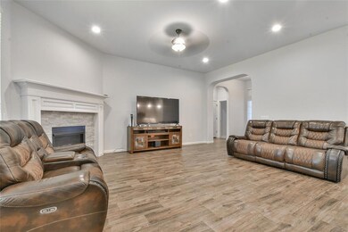 Living area featuring recessed lighting, wood finished floors, arched walkways, a fireplace, and ceiling fan