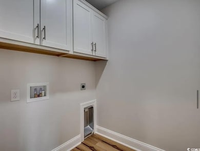 Laundry room featuring electric dryer hookup, cabinet space, baseboards, hookup for a washing machine, and light wood-style flooring