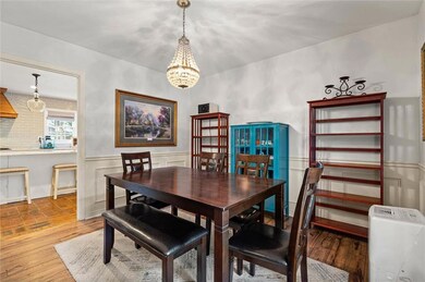 Dining space featuring a chandelier, a wainscoted wall, wood finished floors, and a decorative wall