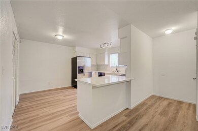 Kitchen featuring a peninsula, stainless steel fridge, light wood-style flooring, and white cabinets