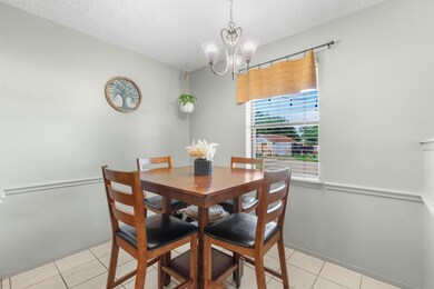 Dining area featuring an inviting chandelier, a textured ceiling, and light tile floors