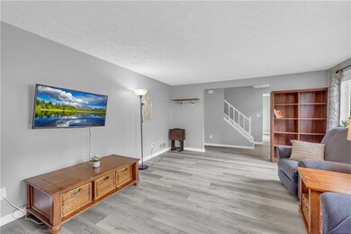Living room featuring stairway, light wood-style floors, a textured ceiling, and baseboards