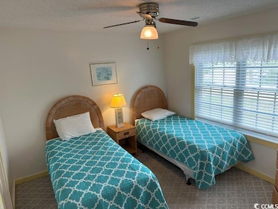 Carpeted bedroom with a textured ceiling and ceiling fan