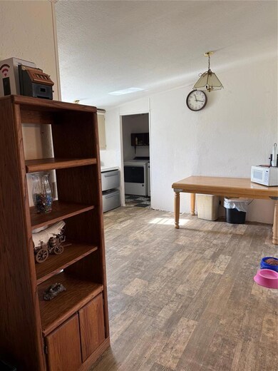 Dining room featuring wood finished floors, washer / dryer, a textured wall, a textured ceiling, and vaulted ceiling