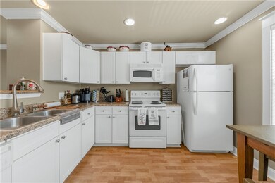 Kitchen with white appliances, crown molding, ligh