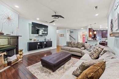 Living area featuring crown molding, stairway, dark wood-style floors, recessed lighting, and a ceiling fan