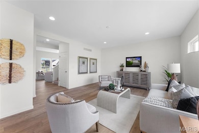 Living room with healthy amount of natural light, wood finished floors, and recessed lighting