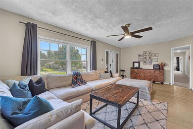 Living room featuring a ceiling fan, light wood-st
