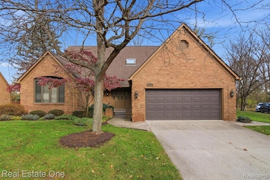 View of front of home with brick siding, driveway, a front lawn, and an attached garage