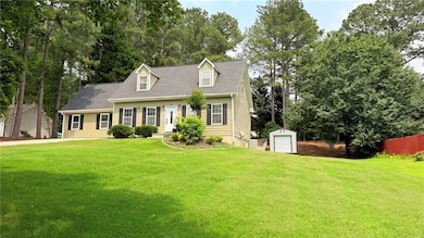 Cape cod home featuring an outdoor structure, a detached garage, and view of wooded area