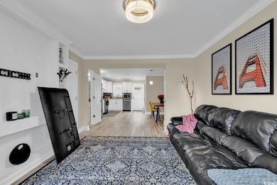 Living room featuring ornamental molding and light hardwood / wood-style floors