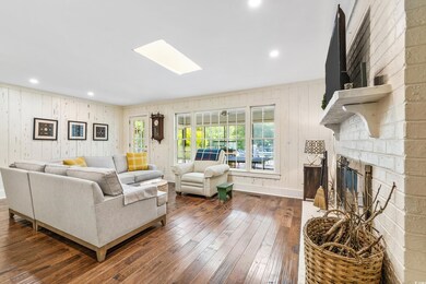 Living room with a stone fireplace, brick wall, an