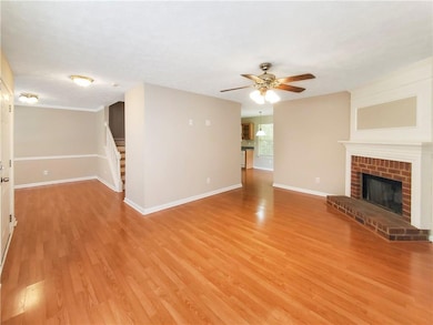 Unfurnished living room featuring light wood-type flooring, baseboards, a ceiling fan, and stairs