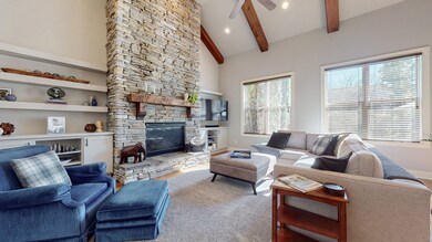 Large family room with hardwood floors, floor-to-ceiling stone gas fireplace with built-ins on both sides, and vaulted ceiling with beams.