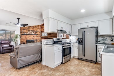 Kitchen featuring appliances with stainless steel finishes, white cabinetry, open floor plan, light tile patterned flooring, and ceiling fan