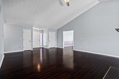 Unfurnished living room with a textured ceiling, lofted ceiling, baseboards, wood finished floors, and a ceiling fan