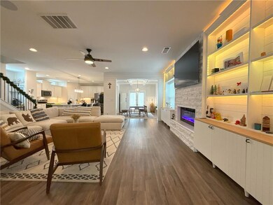 Living area featuring ceiling fan, dark wood-style flooring, a fireplace, stairs, and recessed lighting