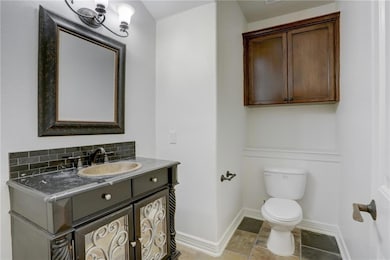 Half bathroom with baseboards, toilet, vanity, an