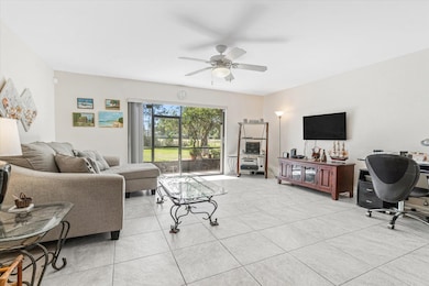 Living room with an office area, ceiling fan, and light tile patterned floors