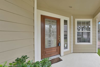 This welcoming front porch has a decorative glass-paneled wooden door, and adjacent windows, providing a cozy and inviting entrance to the home.