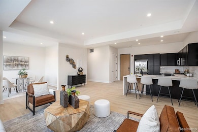 Living room featuring light wood finished floors, a raised ceiling, and recessed lighting