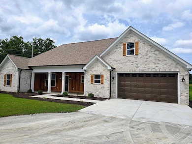 View of front of house featuring covered porch, concrete driveway, brick siding, and a garage