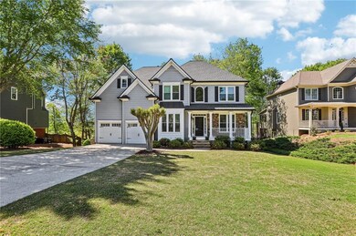View of front of property featuring a shingled roof, a front lawn, concrete driveway, covered porch, and a garage