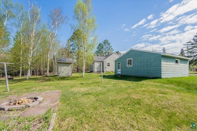 View of grassy yard with an outdoor fire pit and an outbuilding
