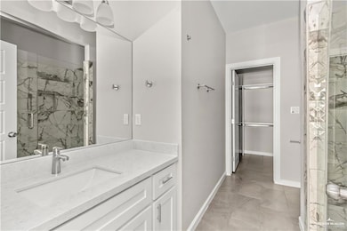 Bathroom with vanity, marble finish floor, baseboards, and a marble finish shower