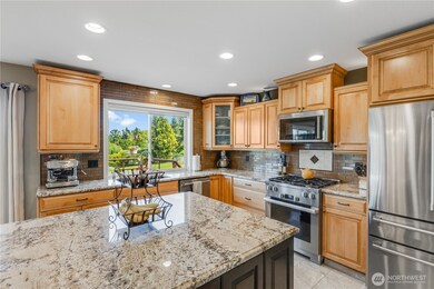 Large kitchen features beveled granite countertops, maple cabinets & ambient lighting below and above.