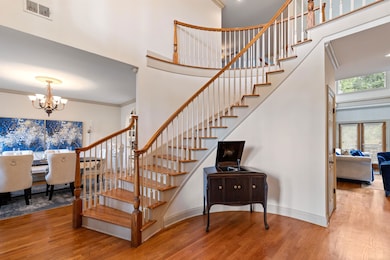Stairs with a notable chandelier, a towering ceiling, hardwood / wood-style floors, and crown molding