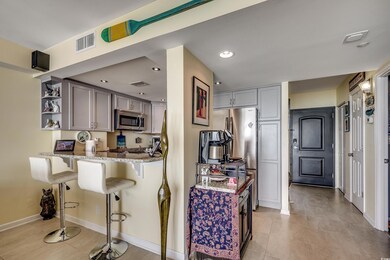 Kitchen featuring appliances with stainless steel finishes, open shelves, light stone countertops, a kitchen bar, and gray cabinetry