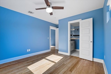 Unfurnished bedroom featuring light wood-style flooring, ensuite bathroom, and ceiling fan