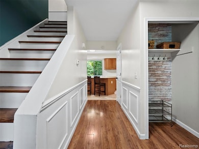 Staircase featuring hardwood / wood-style flooring, wainscoting, and a decorative wall