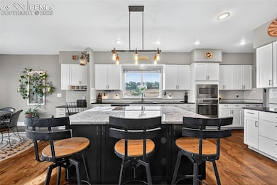 Kitchen featuring dark cabinetry, a kitchen breakfast bar, dark wood-type flooring, and recessed lighting