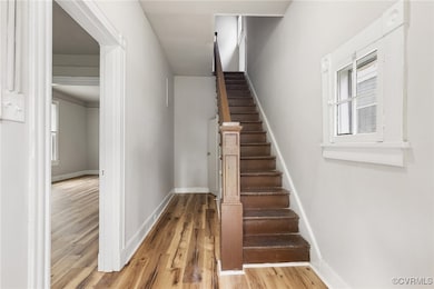 Stairway with wood finished floors, baseboards, an