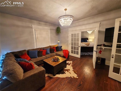Unit 1 Living area with French doors, hardwood / wood-style flooring, a chandelier, and a textured ceiling