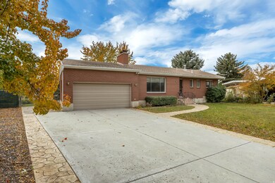 Ranch-style home featuring brick siding, a front yard, concrete driveway, a chimney, and an attached garage