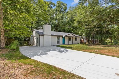 Ranch-style home with driveway, a chimney, and a front lawn