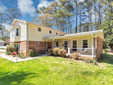 Split level home featuring brick siding, a front lawn, and a porch